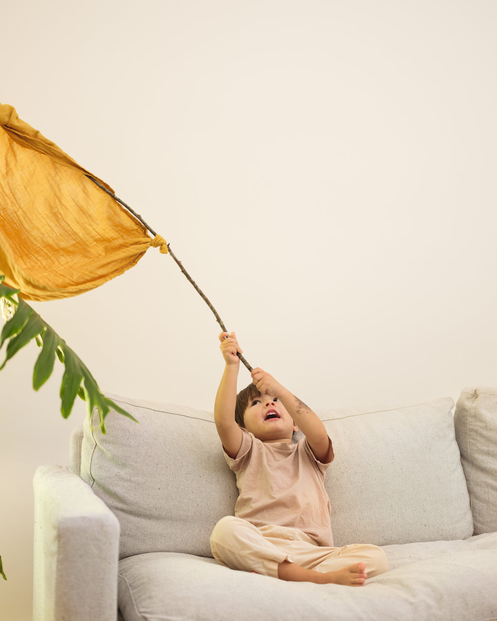 child sitting on couch waiving flag made from a gold play cloth