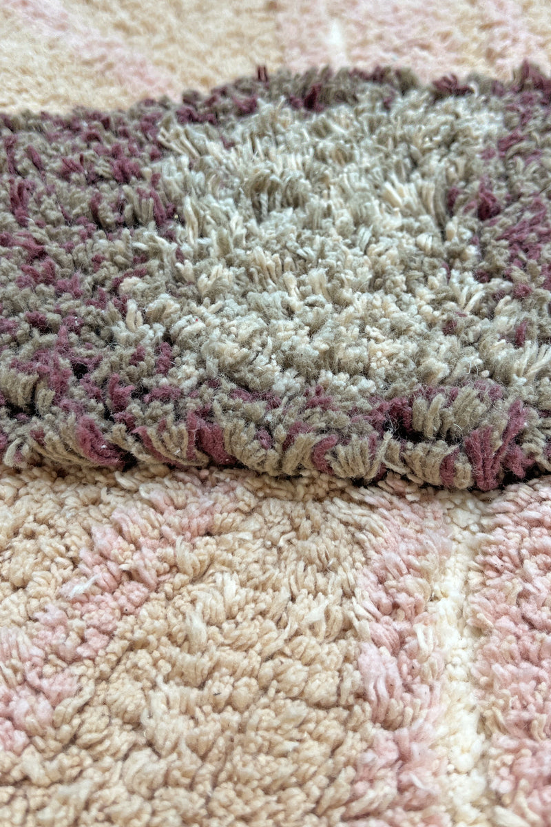 Close-up of a textured rug with a pink and beige pattern