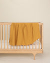 gold organic cotton gauze swaddle on crib
