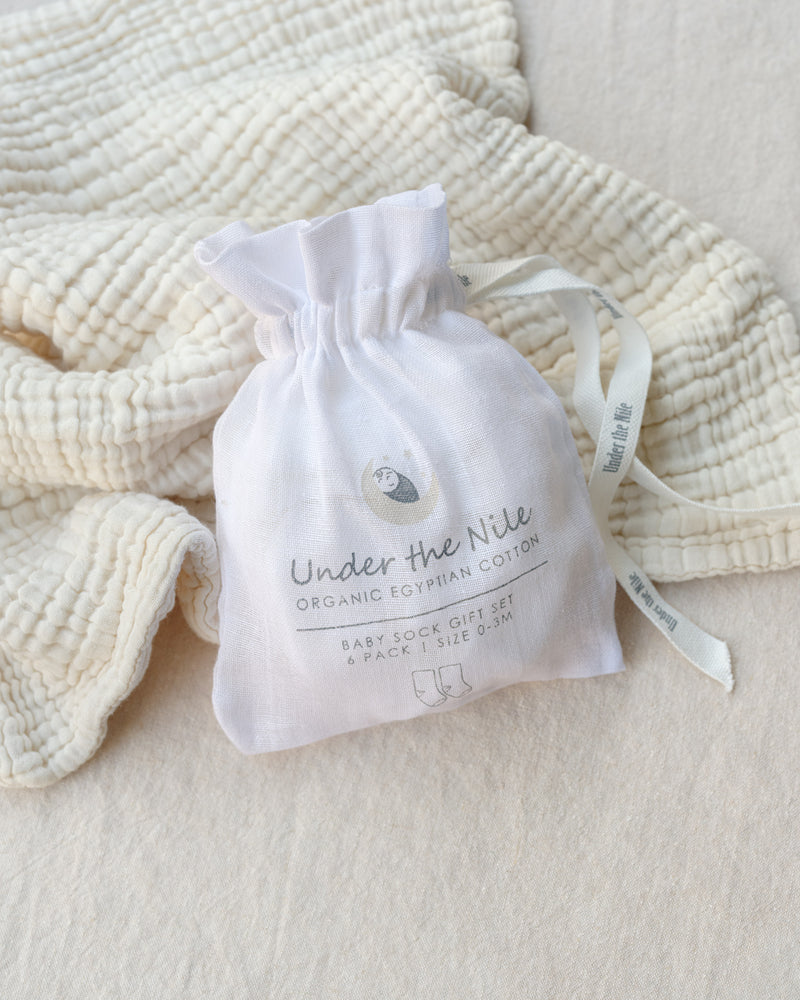 White drawstring bag with 'Under the Nile' branding on a textured white fabric background