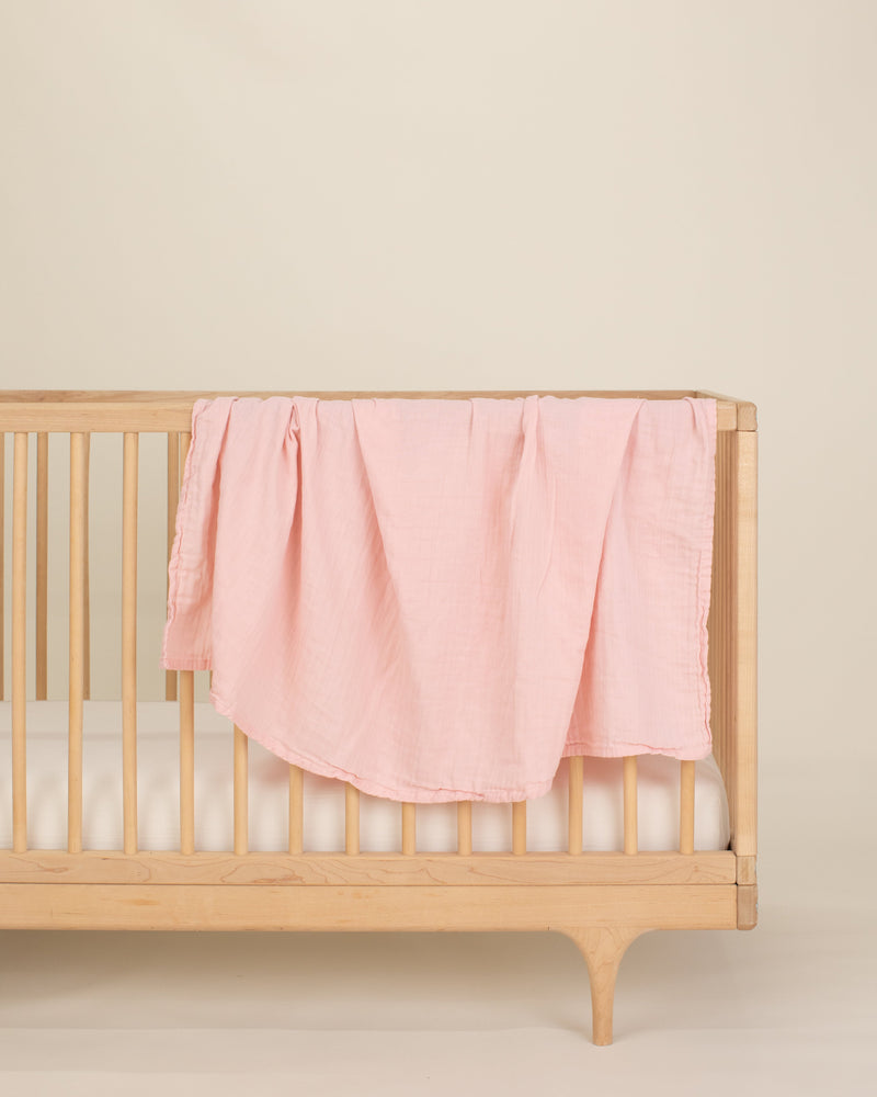 light pink organic cotton gauze swaddle on crib 