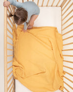 gold organic cotton gauze swaddle in crib 