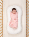 baby wrapped in light pink organic cotton swaddle