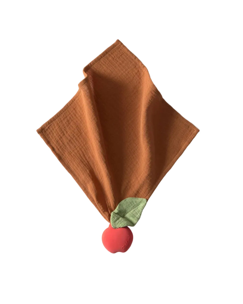Brown textured fabric with a red ball and green leaf on a white background