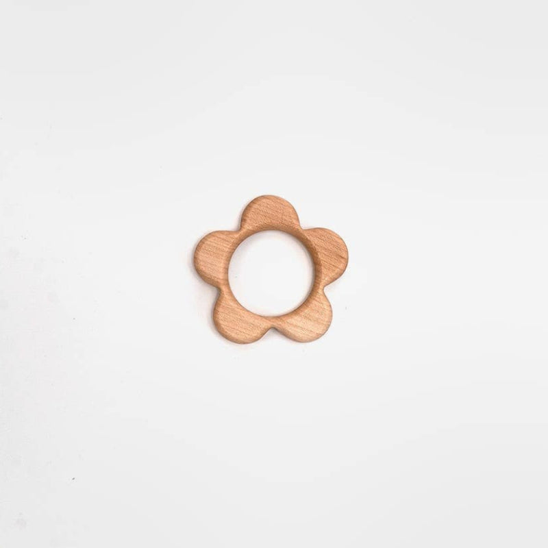 A small flower-shaped wooden teether or ring toy with a natural light wood finish, centered on a plain white background.