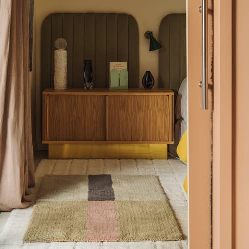 Wooden cabinet with decorative items in a room with a patterned rug.