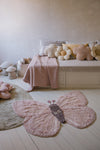 Children's room with a butterfly rug on the floor and a bed with decorative pillows in the background.
