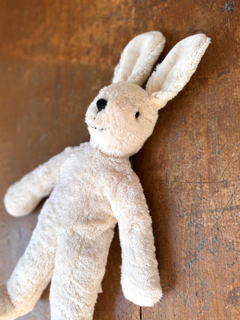 White plush bunny toy on a textured brown background