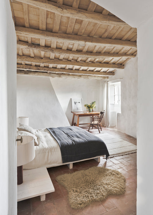 Cozy bedroom with wooden beams, bed, and desk.