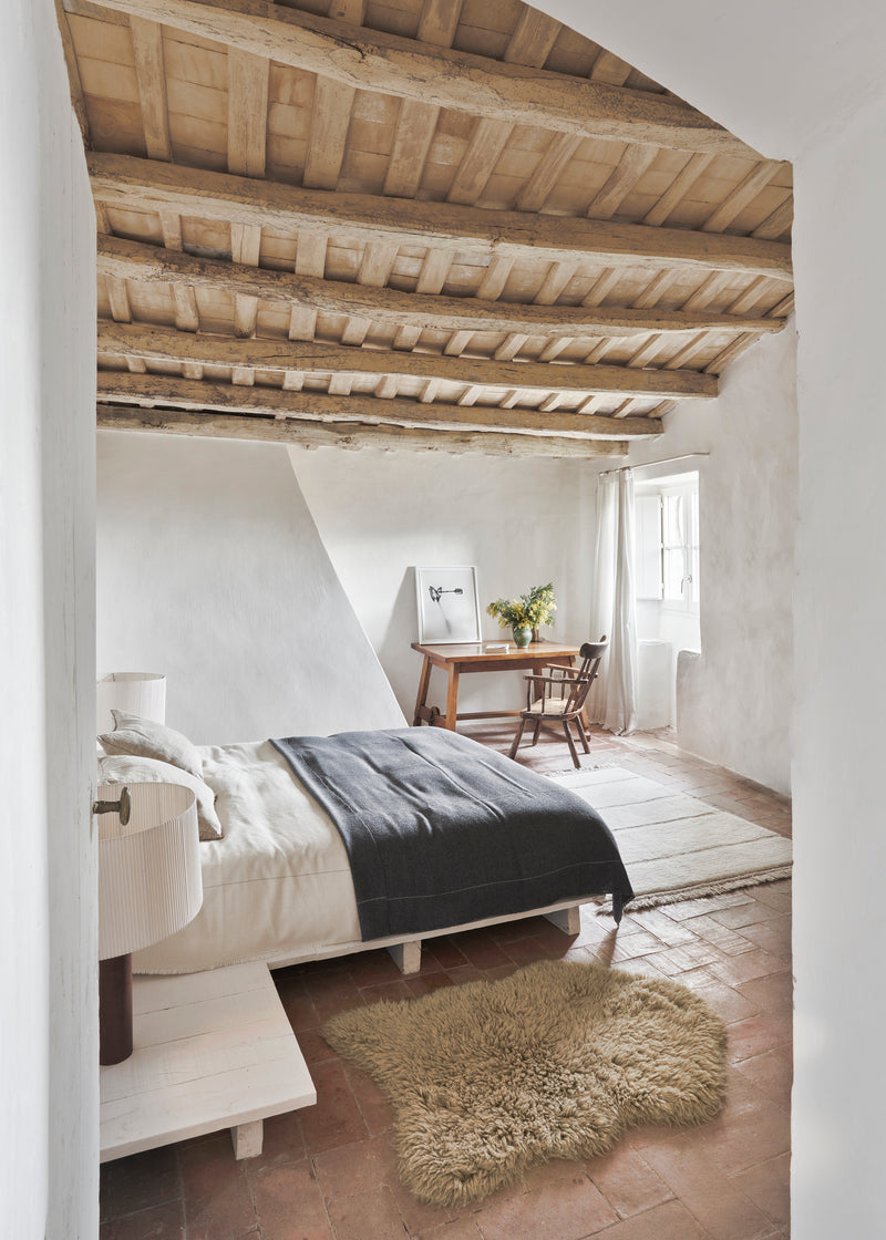 Cozy bedroom with wooden beams, bed, and desk.