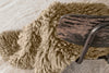 Close-up of a wooden chair with a textured beige cushion on a light wood floor.