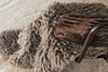 Close-up of a textured blanket draped over a wooden chair on a textured surface.