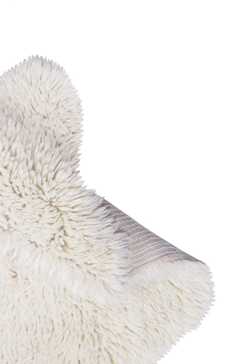 Close-up of a fluffy white sheep rug corner on a white background