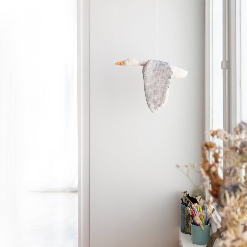 Decorative goose sculpture on a white wall with a window and plant in the background