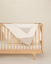 grey organic cotton gauze burp cloth and geo baby blanket on crib