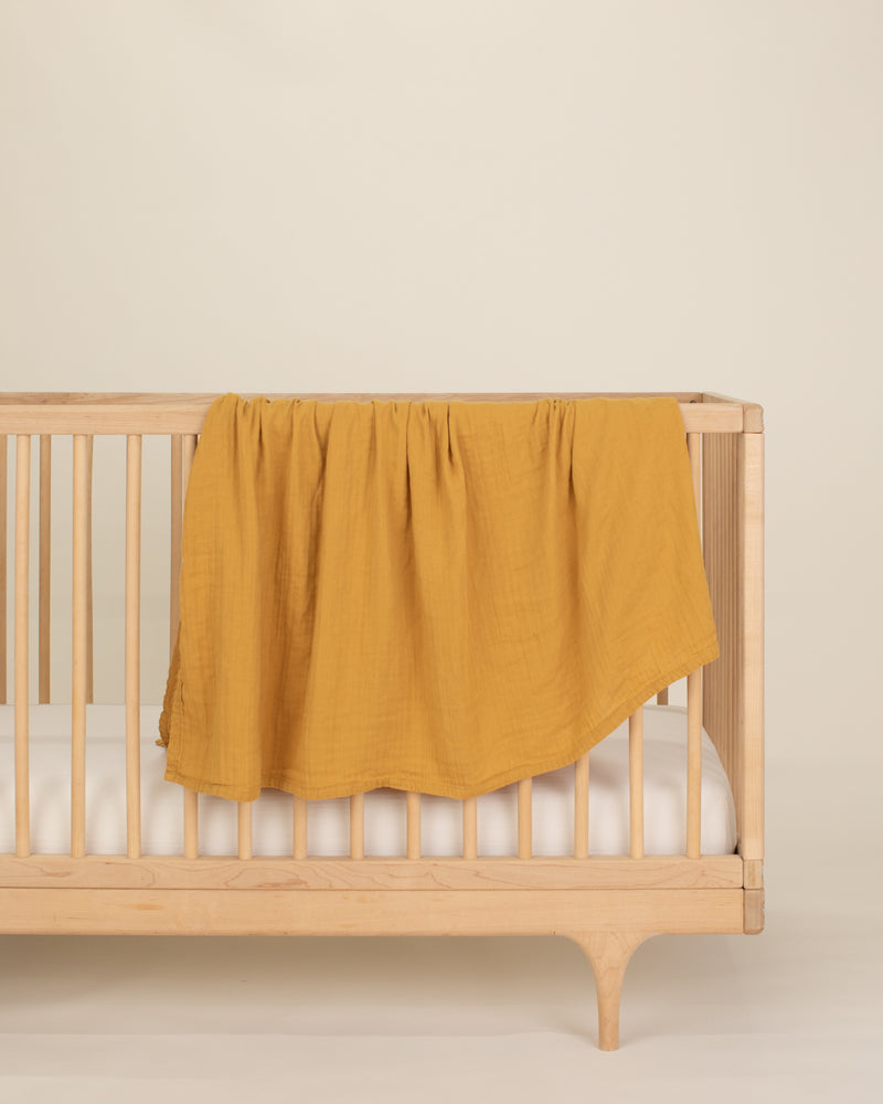 gold organic cotton gauze swaddle on crib