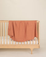 rust organic cotton gauze swaddle on crib