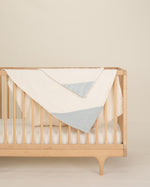 aqua organic cotton gauze burp cloth and geo baby blanket on crib