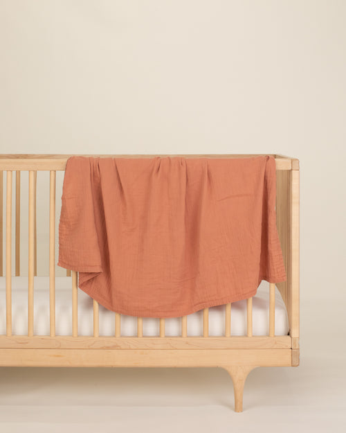 rust organic cotton gauze swaddle on crib