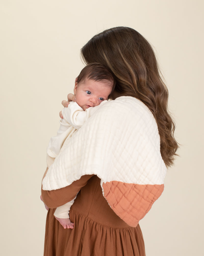 mother and baby with rust organic cotton gauze geo burp cloth 