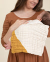 mother and baby with gold organic cotton gauze geo burp cloth 
